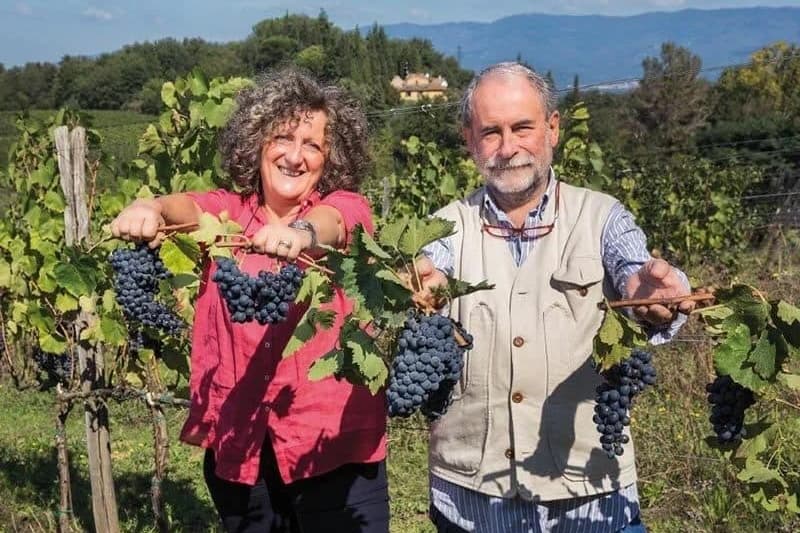 Dai nostri vignaioli, in Italia: due vignaioli mostrano grappoli d’uva tra i loro filari